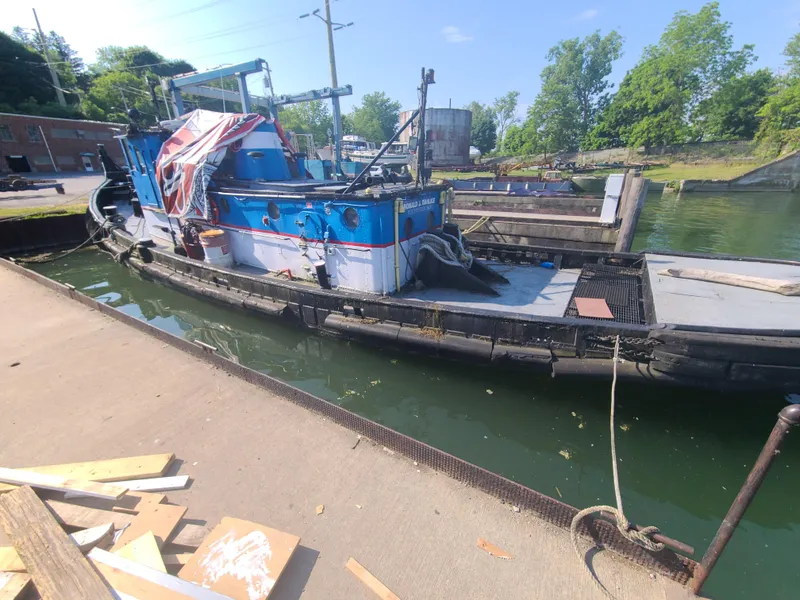 Slide: The Image of Alt text: 1903 Johnson Brother Tug 64 docked at a marina. - 19