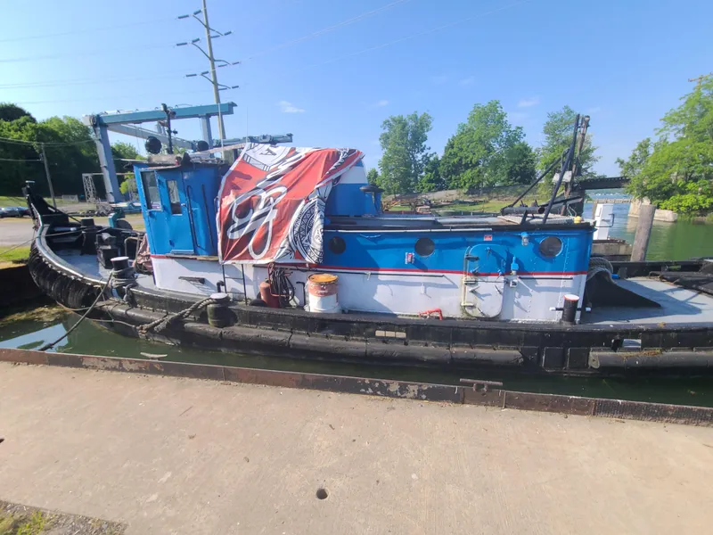 Slide: The Image of 1903 Johnson Brother Tug 64 docked, blue and white hull, outdoor setting. - 21