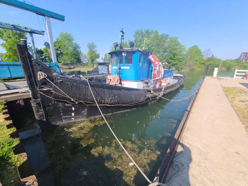 Slide: The Image of 1903 Johnson Brother Tug 64 docked in a serene canal. - 22
