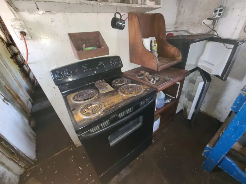 Slide: The Image of Old kitchen with a black stove, open fridge, and wooden shelves, Johnson Brother Tug 64, 1903. - 33