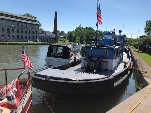Slide: The Image of Historic 1903 Johnson Brother Tug 64 docked on a sunny day with American flags. - 7
