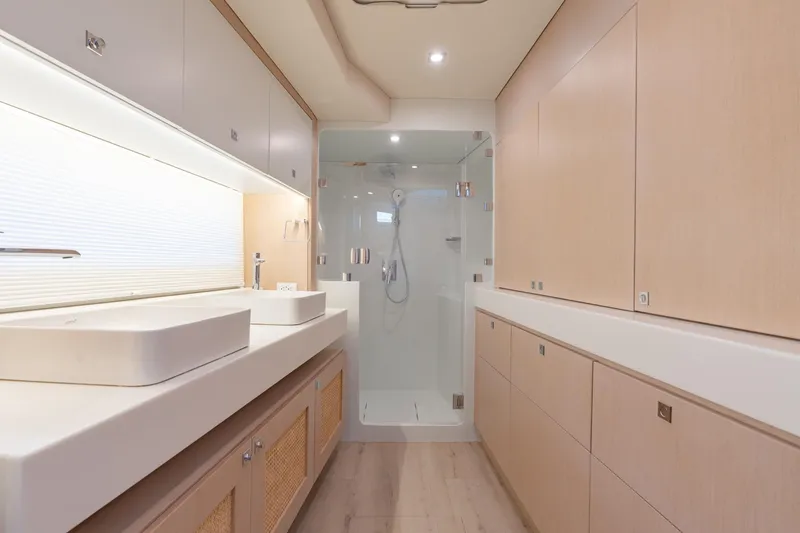 Slide: The Image of Modern yacht bathroom with dual sinks, glass shower, and wooden cabinetry, Two Oceans 555, 2025 model. - 36