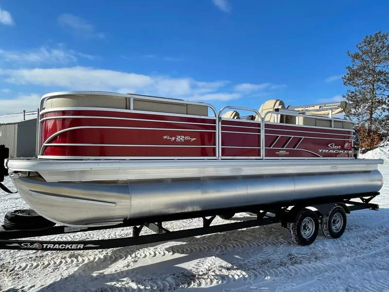 Slide: The Image of 2023 Sun Tracker Party Barge 22 DLX pontoon boat on trailer in snowy setting. - 2