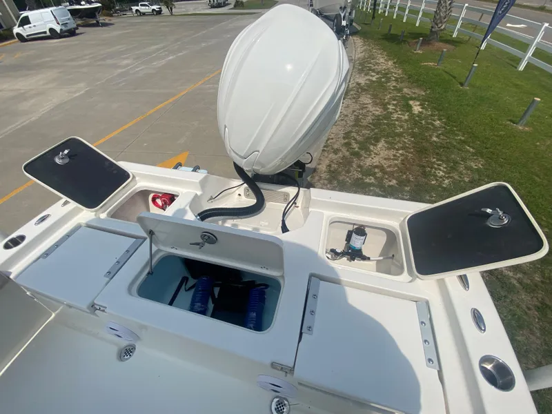 Slide: The Image of 2024 Key West 230 Bay Reef boat with open storage compartments and outboard motor. - 19