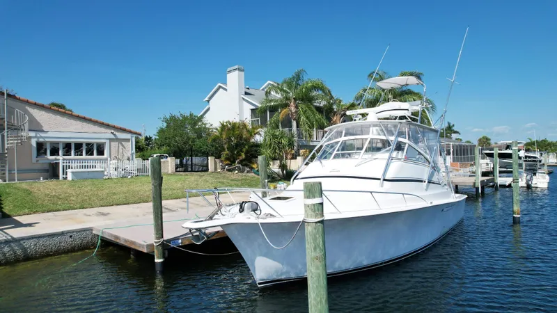Slide: The Image of 2003 Ocean 40 Super Sport yacht docked by waterfront homes under clear blue sky. - 2