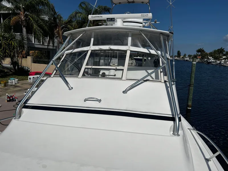 Slide: The Image of 2003 Ocean 40 Super Sport boat docked by waterfront homes, clear sky. - 28