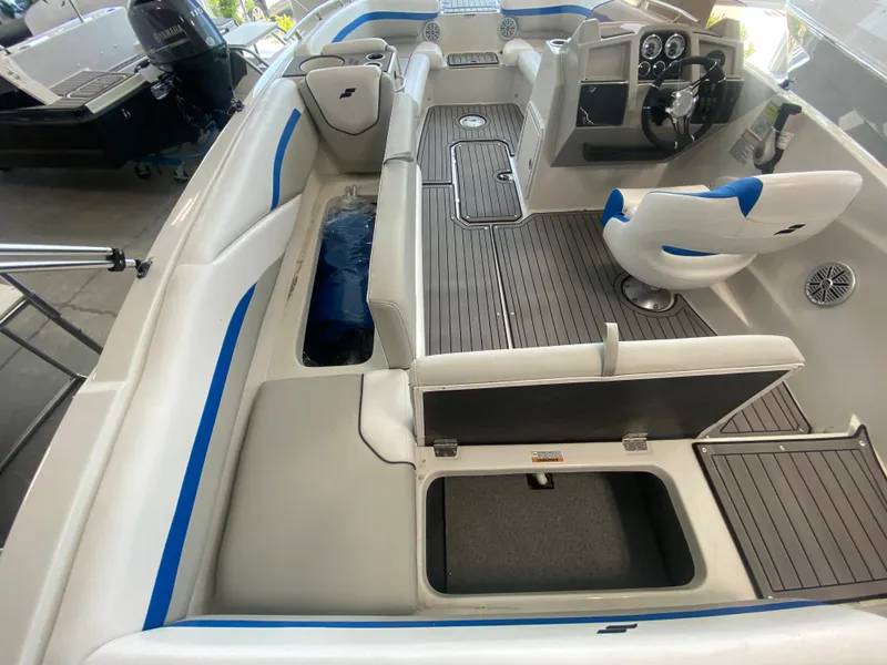 Slide: The Image of 2024 Starcraft SVX 211 boat interior with white and blue seating, steering console, and storage compartments. - 8