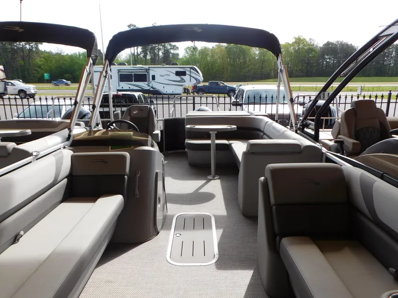 Slide: The Image of 2023 Bennington 22 SXL pontoon boat interior with seating and table, parked near RVs. - 2