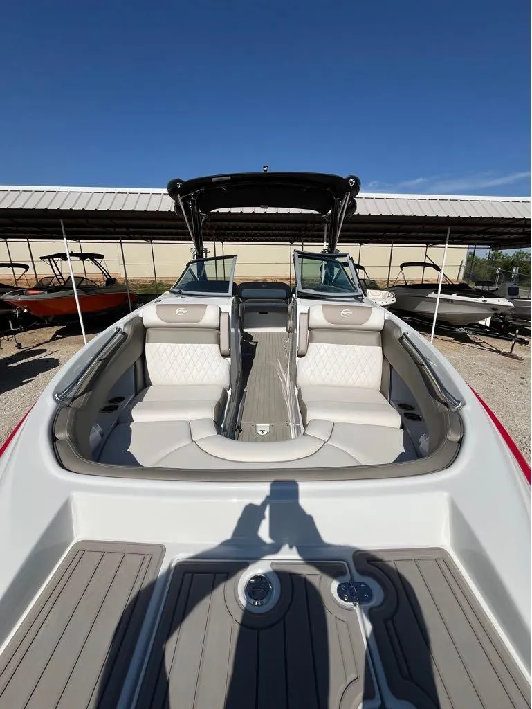 Slide: The Image of 2023 Crownline E255 Surf boat interior with seating and deck, under clear blue sky. - 7