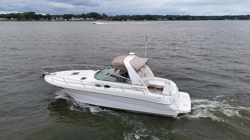 The Image of 1999 Sea Ray 310 Sundancer cruising on a calm lake under cloudy skies. - 0