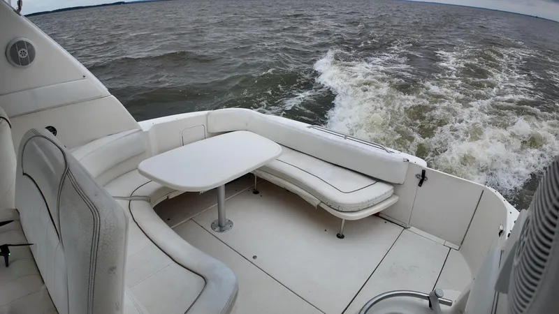 Slide: The Image of 1999 Sea Ray 310 Sundancer boat interior with white seating and table on open water. - 11