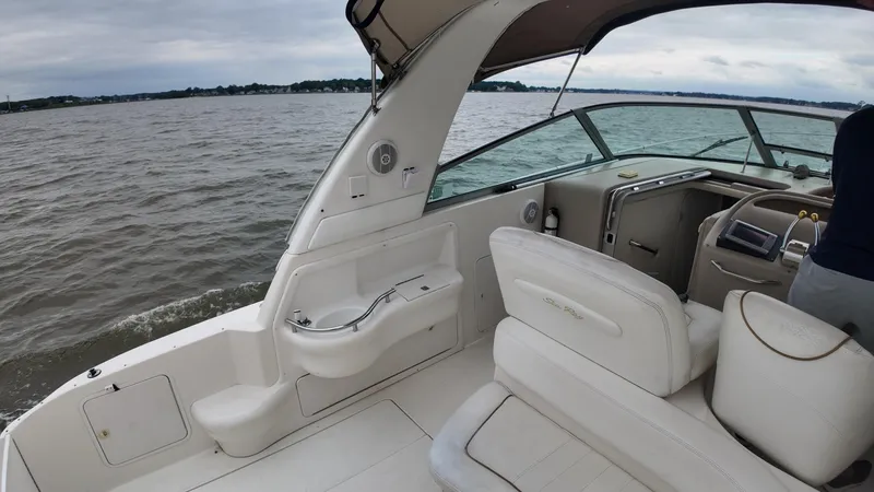 Slide: The Image of 1999 Sea Ray 310 Sundancer boat interior with white seating, cruising on a calm lake. - 14