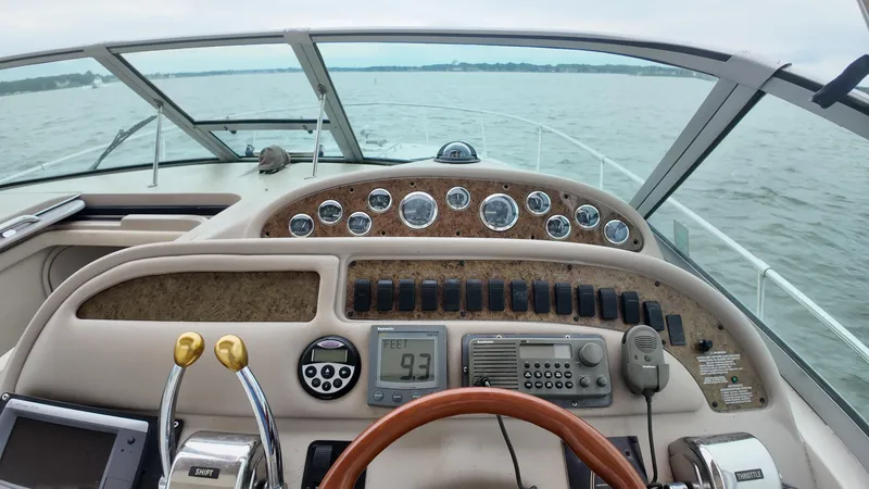 Slide: The Image of 1999 Sea Ray 310 Sundancer dashboard with gauges and controls, overlooking calm waters. - 18