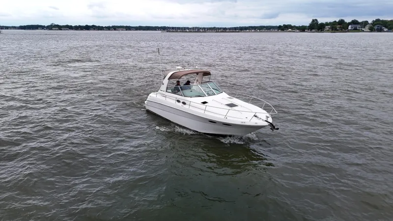 Slide: The Image of 1999 Sea Ray 310 Sundancer cruising on a calm lake under cloudy skies. - 2