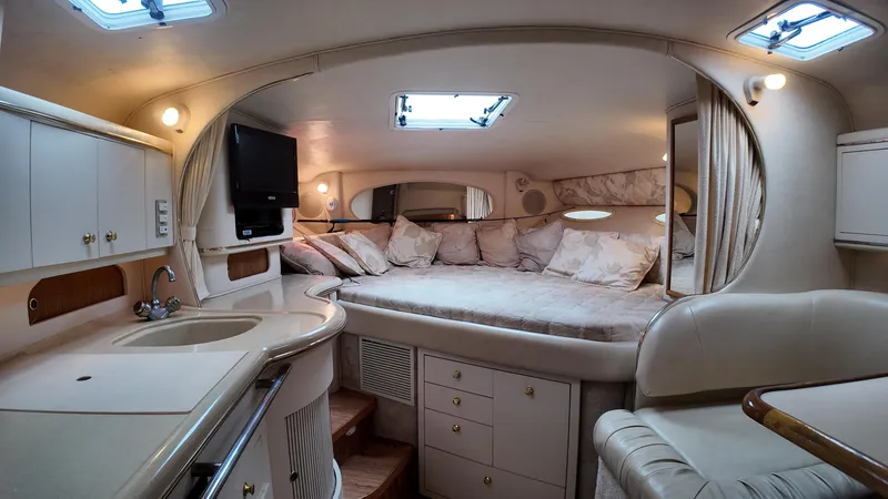 Slide: The Image of 1999 Sea Ray 310 Sundancer cabin interior with bed, kitchenette, and seating area. - 21