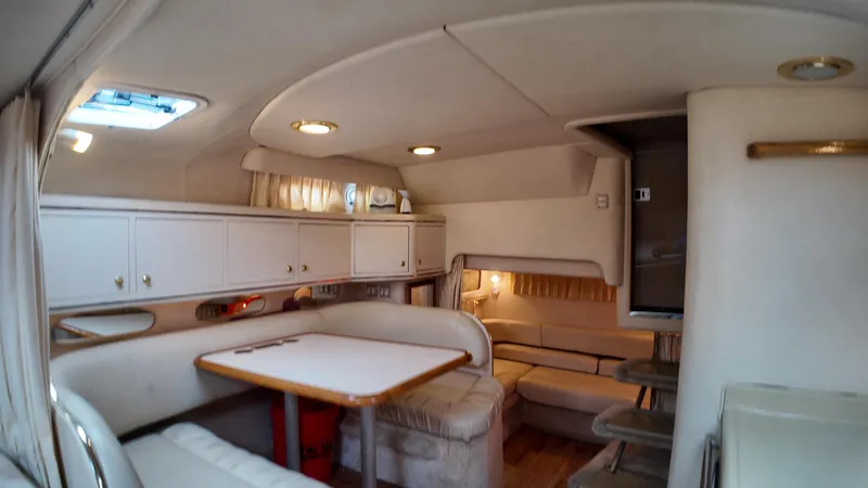 Slide: The Image of Interior of 1999 Sea Ray 310 Sundancer yacht, featuring cozy seating and dining area. - 22