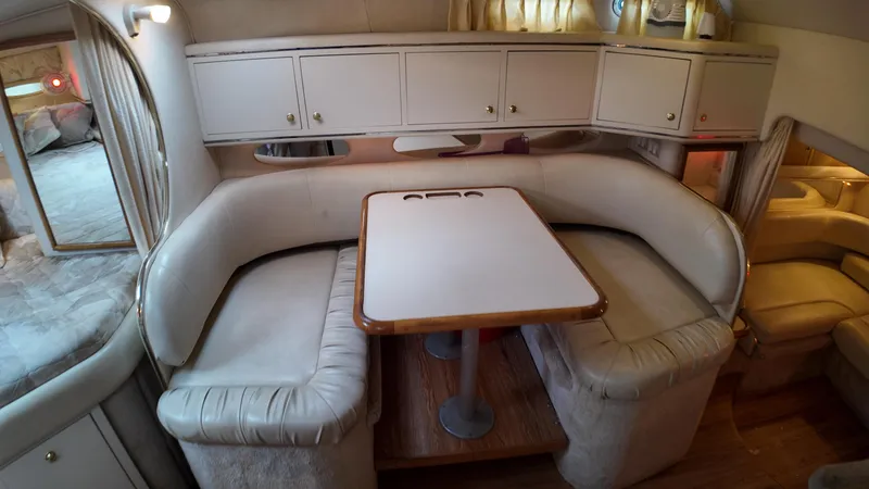 Slide: The Image of 1999 Sea Ray 310 Sundancer interior with cozy dining area and cushioned seating. - 24