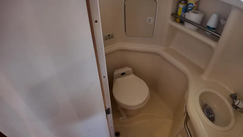 Slide: The Image of 1999 Sea Ray 310 Sundancer bathroom with toilet, sink, and storage shelves. - 28