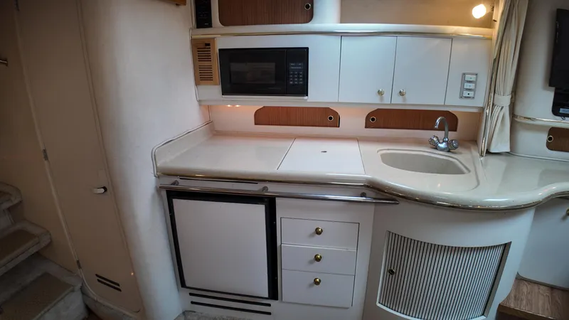 Slide: The Image of 1999 Sea Ray 310 Sundancer galley with microwave, sink, and storage cabinets. - 29