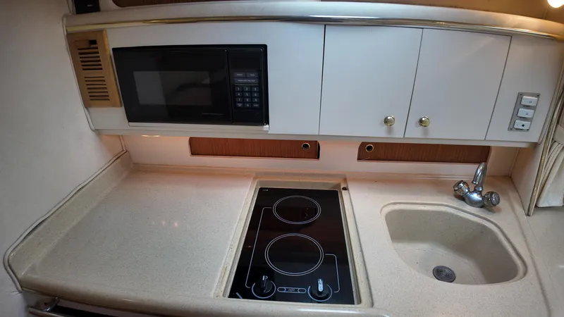 Slide: The Image of 1999 Sea Ray 310 Sundancer kitchen with microwave, stovetop, and sink. - 30