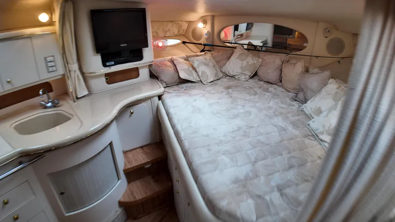 Slide: The Image of 1999 Sea Ray 310 Sundancer cabin interior with bed, TV, and sink. - 31