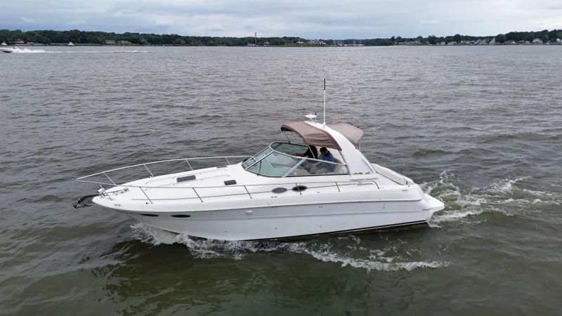 Slide: The Image of 1999 Sea Ray 310 Sundancer cruising on a lake under cloudy skies. - 34