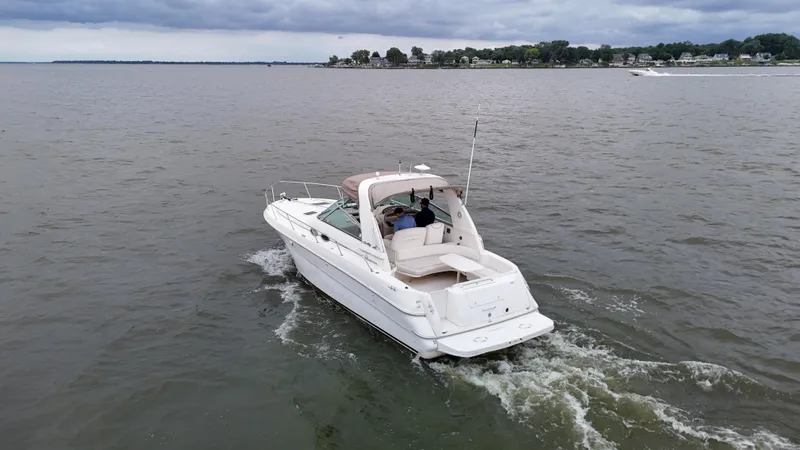Slide: The Image of 1999 Sea Ray 310 Sundancer cruising on a calm lake under cloudy skies. - 4
