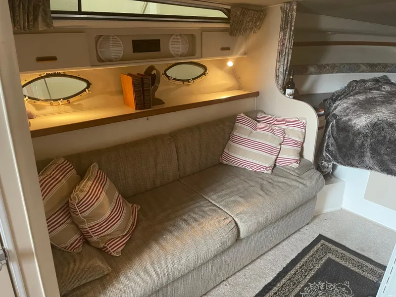 Slide: The Image of 1993 Wellcraft St Tropez 3200 interior with cozy seating, striped pillows, and ambient lighting. - 29