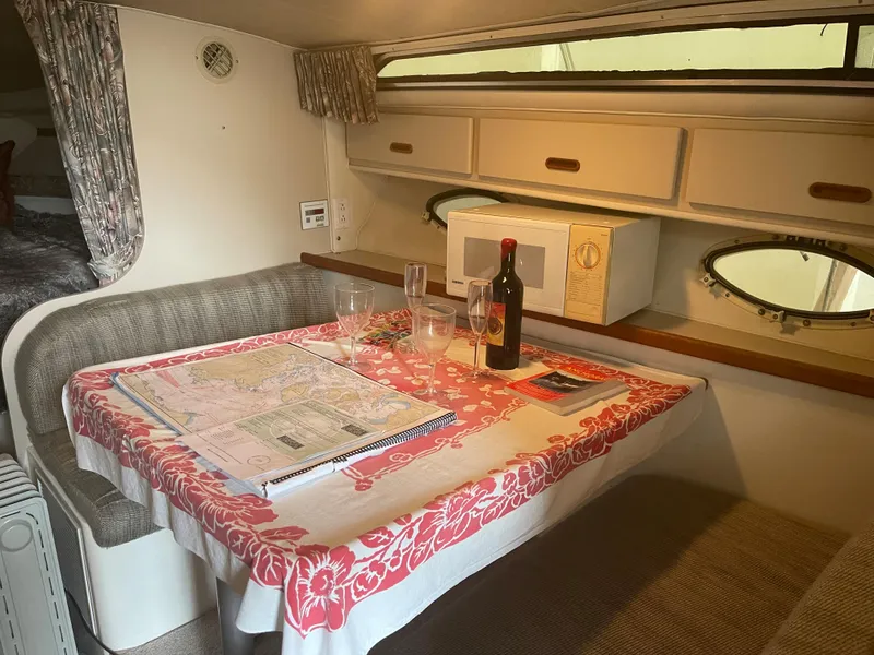 Slide: The Image of 1993 Wellcraft St Tropez 3200 cabin dining area with table, wine bottle, and maps. - 4