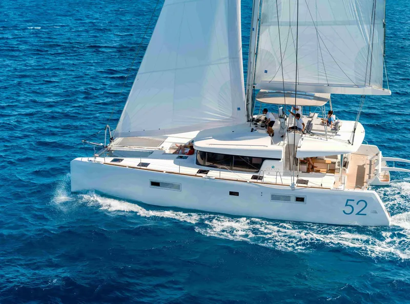The Image of 2020 Lagoon 52 F catamaran sailing on clear blue ocean waters. - 1