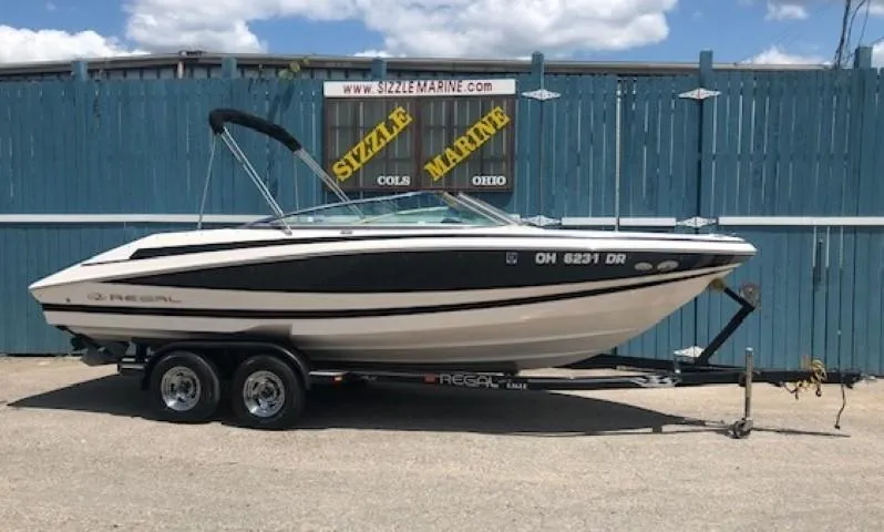 The Image of 2004 Regal 2200 Bowrider boat on trailer in front of blue fence. - 0