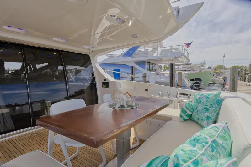 Slide: The Image of 2015 Azimut 64 Flybridge yacht with outdoor dining area and marina view. - 18