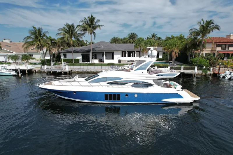 Slide: The Image of 2015 Azimut 64 Flybridge yacht cruising near waterfront homes. - 4