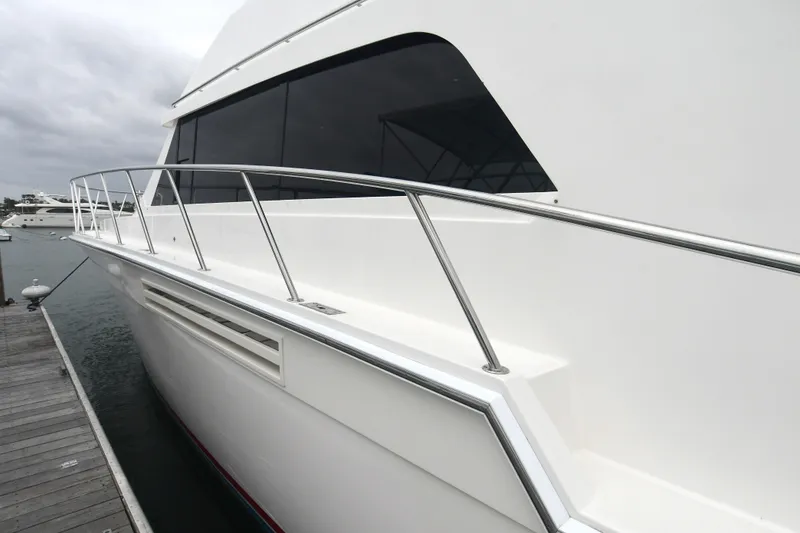 Slide: The Image of 1988 Bertram 54 Convertible yacht docked, showcasing sleek white exterior and stainless steel railings. - 22