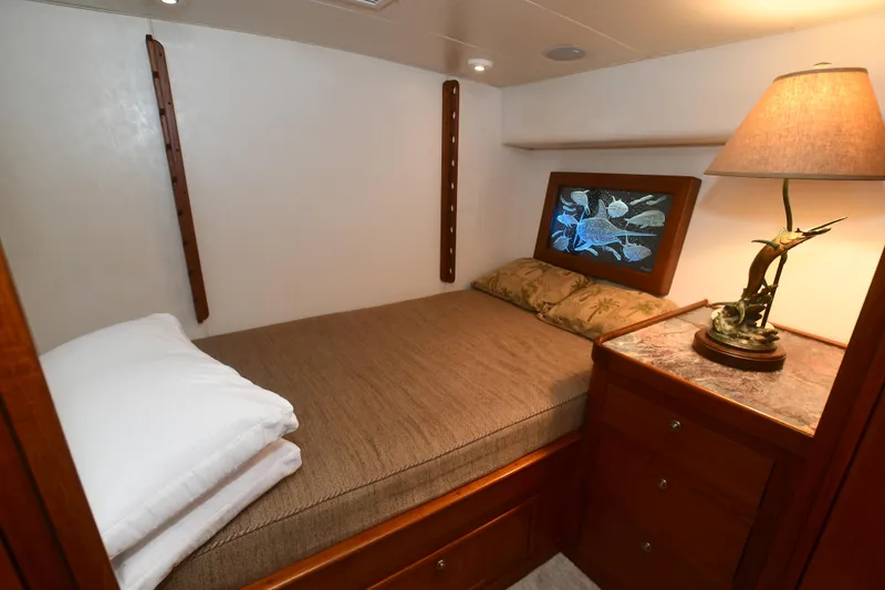 Slide: The Image of Cozy bedroom in 1988 Bertram 54 Convertible yacht with bed, lamp, and wooden cabinets. - 42