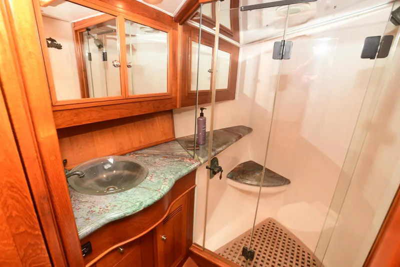 Slide: The Image of 1988 Bertram 54 Convertible yacht bathroom with glass shower, wooden cabinetry, and marble countertop. - 45