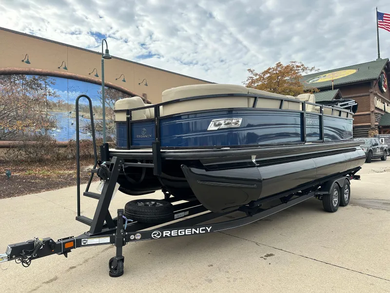 Slide: The Image of 2023 Regency 230 LE3 pontoon boat on a trailer, parked outdoors. - 1
