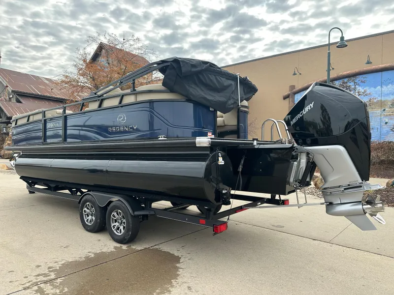 Slide: The Image of 2023 Regency 230 LE3 pontoon boat on a trailer with Mercury outboard motor. - 2