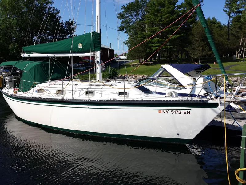Slide: The Image of 1983 Watkins 32 sailboat docked on a calm lake with green canopy. - 0