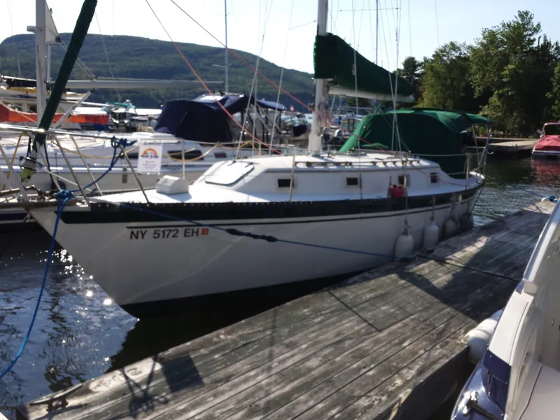 Slide: The Image of Sailboat docked at marina, Watkins 32 model, 1983, with scenic mountain backdrop. - 1