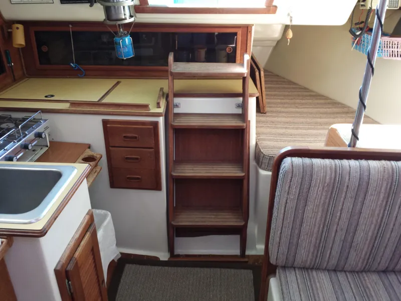 Slide: The Image of Interior of a 1983 Watkins 32 sailboat with wooden cabinetry and striped seating. - 14