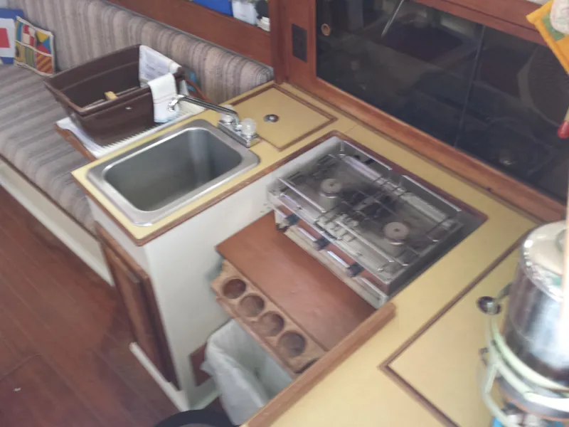 Slide: The Image of Compact kitchen area in a 1983 Watkins 32 boat, featuring a sink and stove. - 16