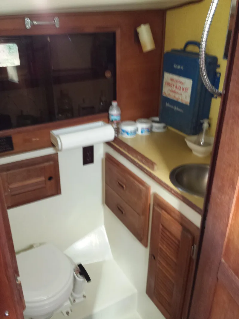 Slide: The Image of 1983 Watkins 32 boat bathroom with wooden cabinets, sink, and marine toilet. - 26