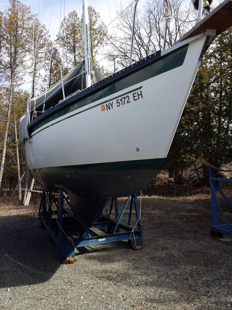 Slide: The Image of 1983 Watkins 32 sailboat on stands, outdoors, with trees in the background. - 39