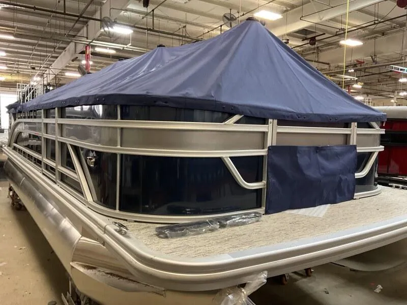 Slide: The Image of 2025 Bennington 22 SF pontoon boat with blue cover in warehouse setting. - 24
