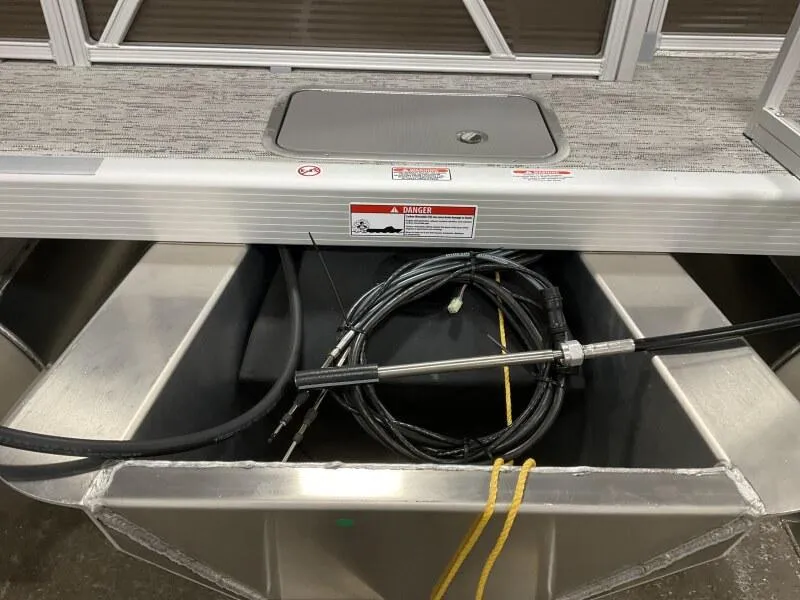 Slide: The Image of 2025 Bennington 188 SS Family Fish Pontoon storage compartment with cables and warning label. - 10