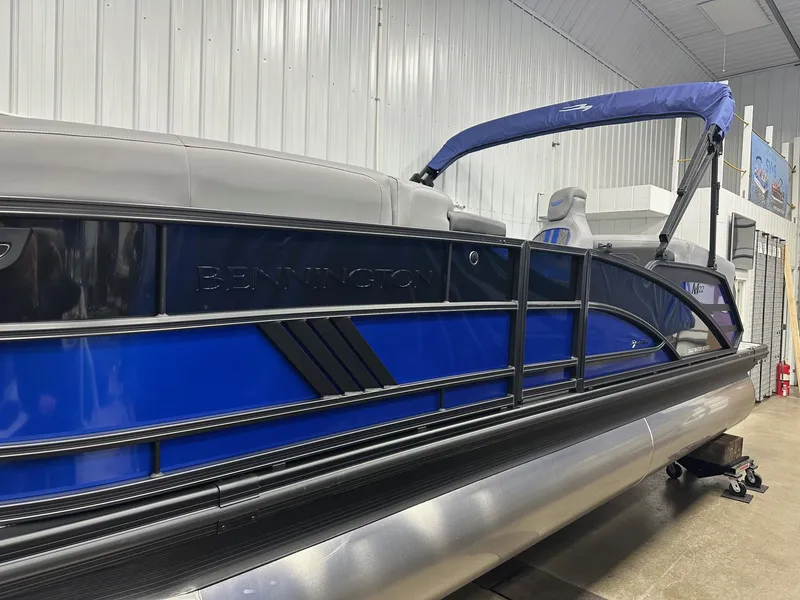 Slide: The Image of 2025 Bennington 22 MFB Tritoon with blue and black design in showroom. - 21