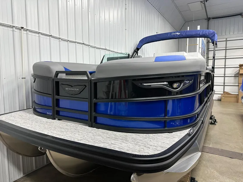 Slide: The Image of 2025 Bennington 22 MFB Tritoon boat in showroom, featuring sleek blue and black design. - 22