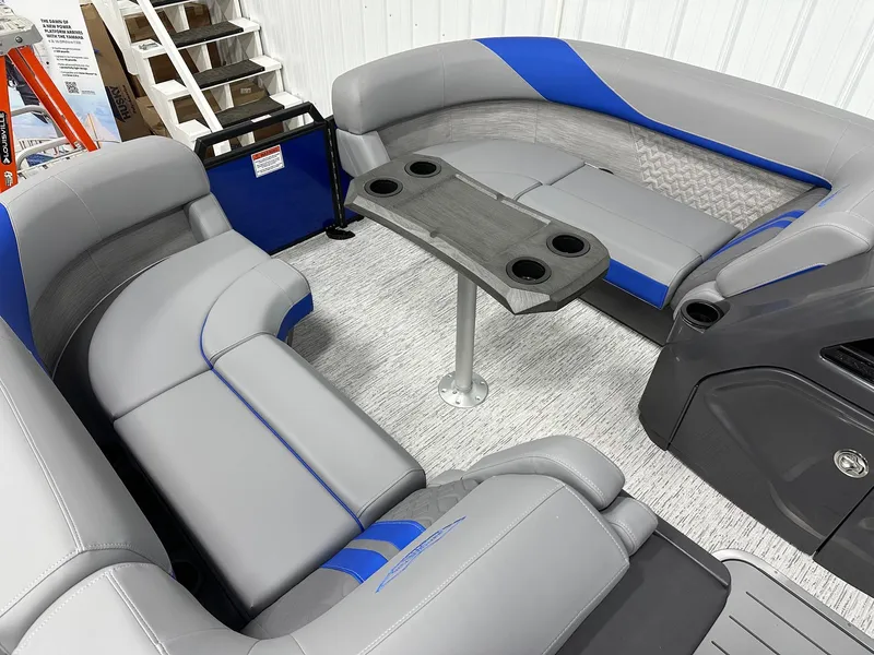 Slide: The Image of 2025 Bennington 22 MFB Tritoon interior with gray and blue seating, table, and cup holders. - 32