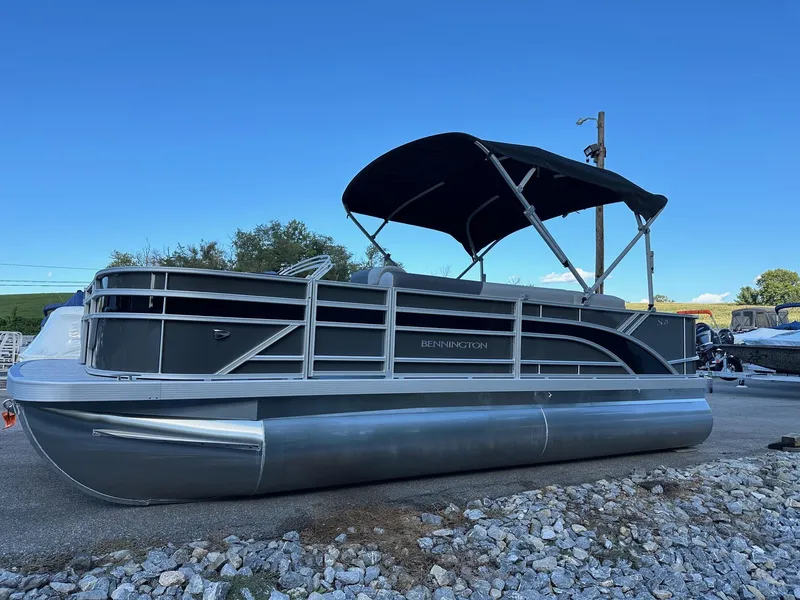 The Image of 2025 Bennington 21 SF pontoon boat with canopy, parked on gravel. - 1